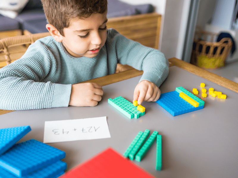 Young child learning math with colorful blocks at the kitchen table
